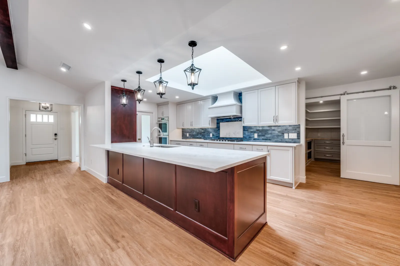 Open-concept kitchen with burgundy island and blue tile backsplash