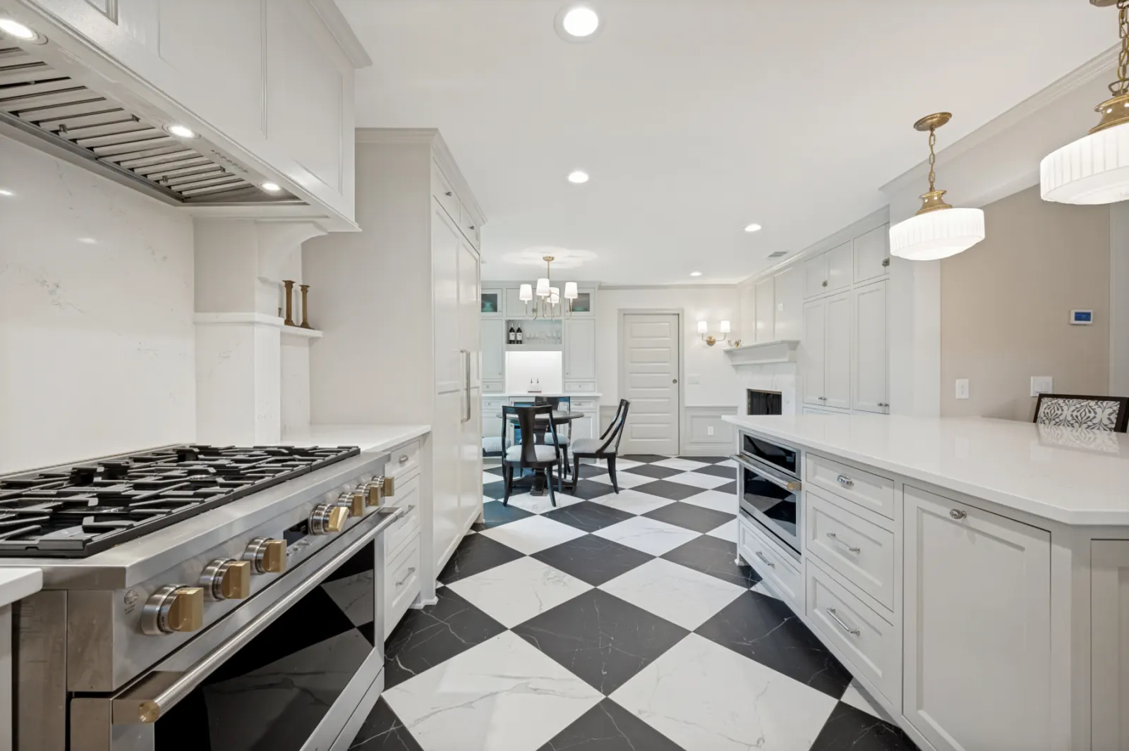 Black and white checkered floor kitchen with quartz counters and brass pendants