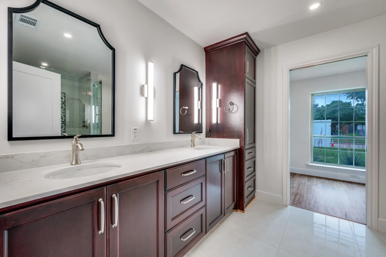 Burgundy cabinetry double vanity with arched mirrors and marble counters