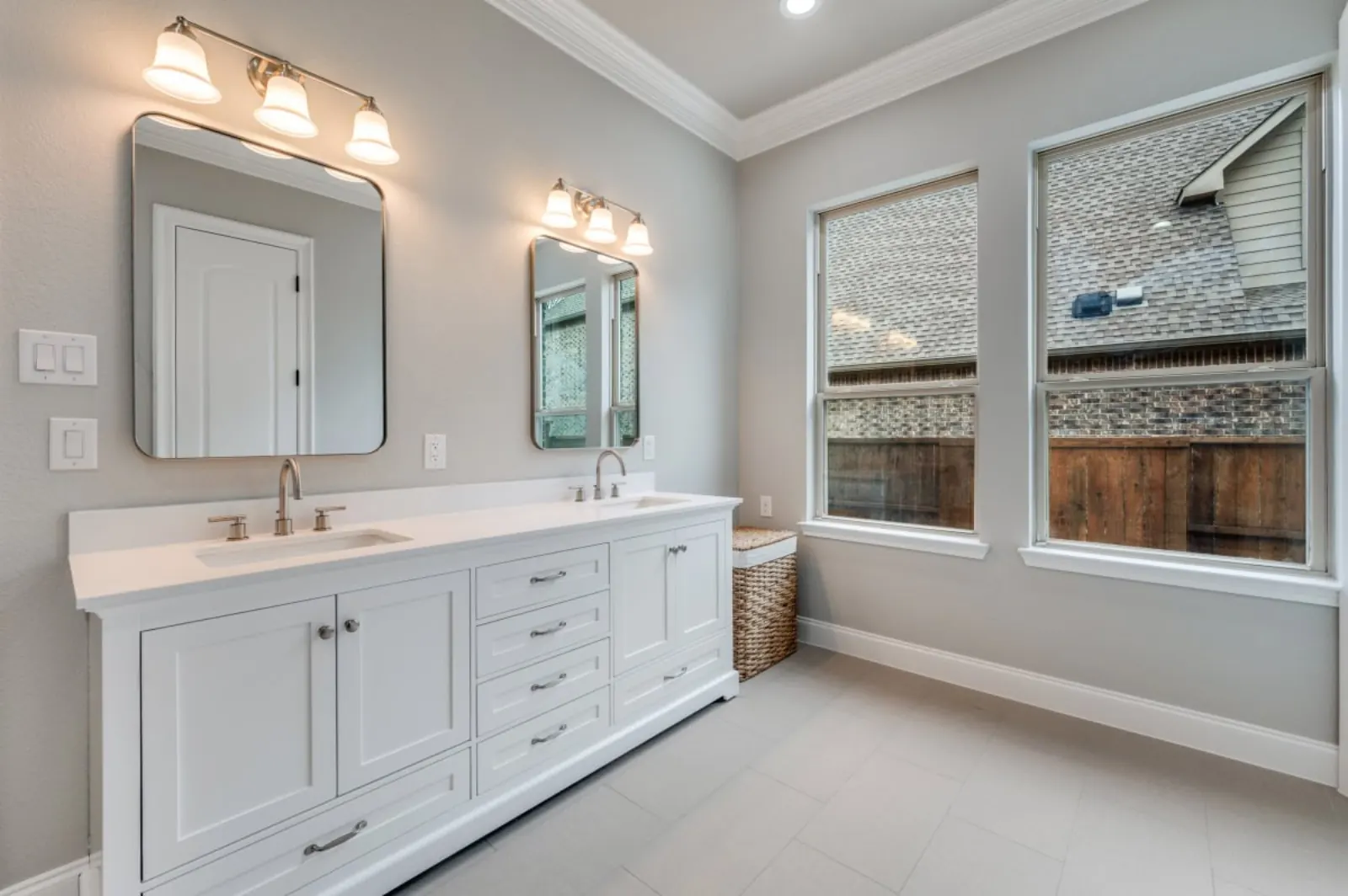 Bright white double vanity with brushed nickel fixtures and large windows