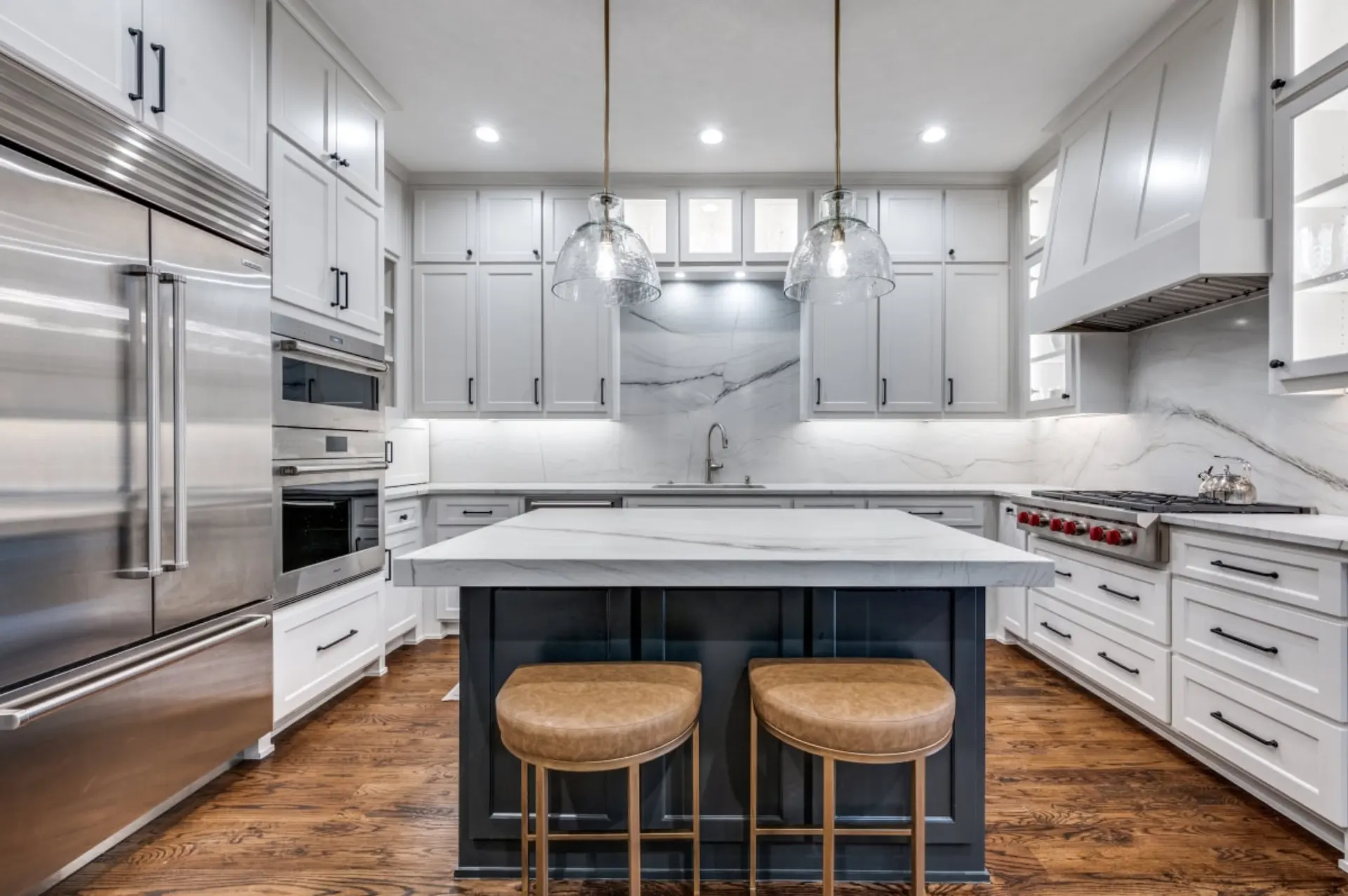 Modern white kitchen with marble island and navy cabinetry
